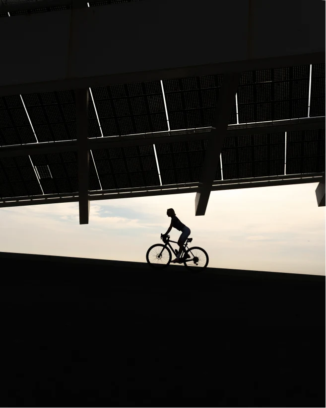 Cyclist silhouetted beneath a geometric roof