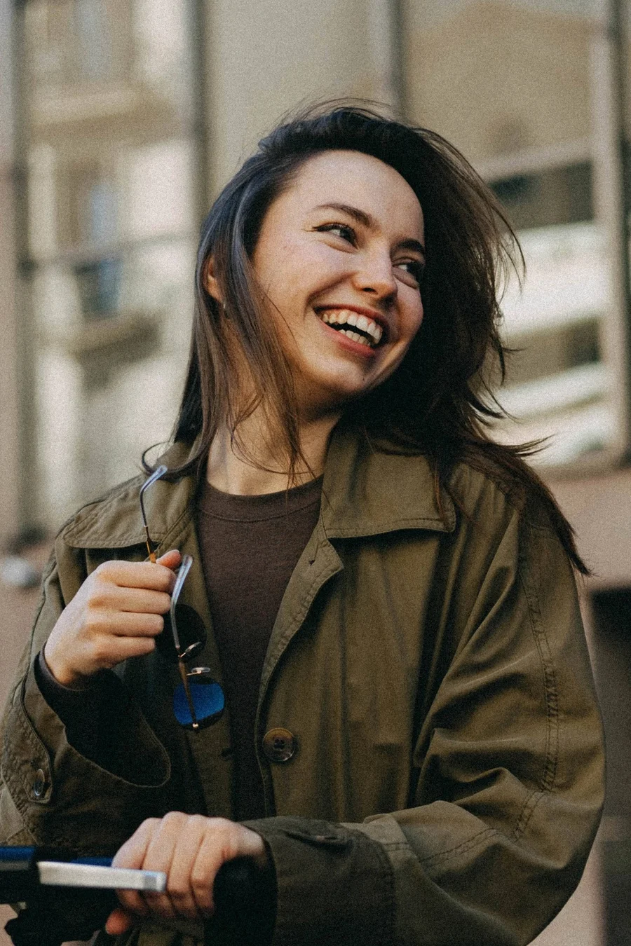 Woman smiling on a city street in a green coat