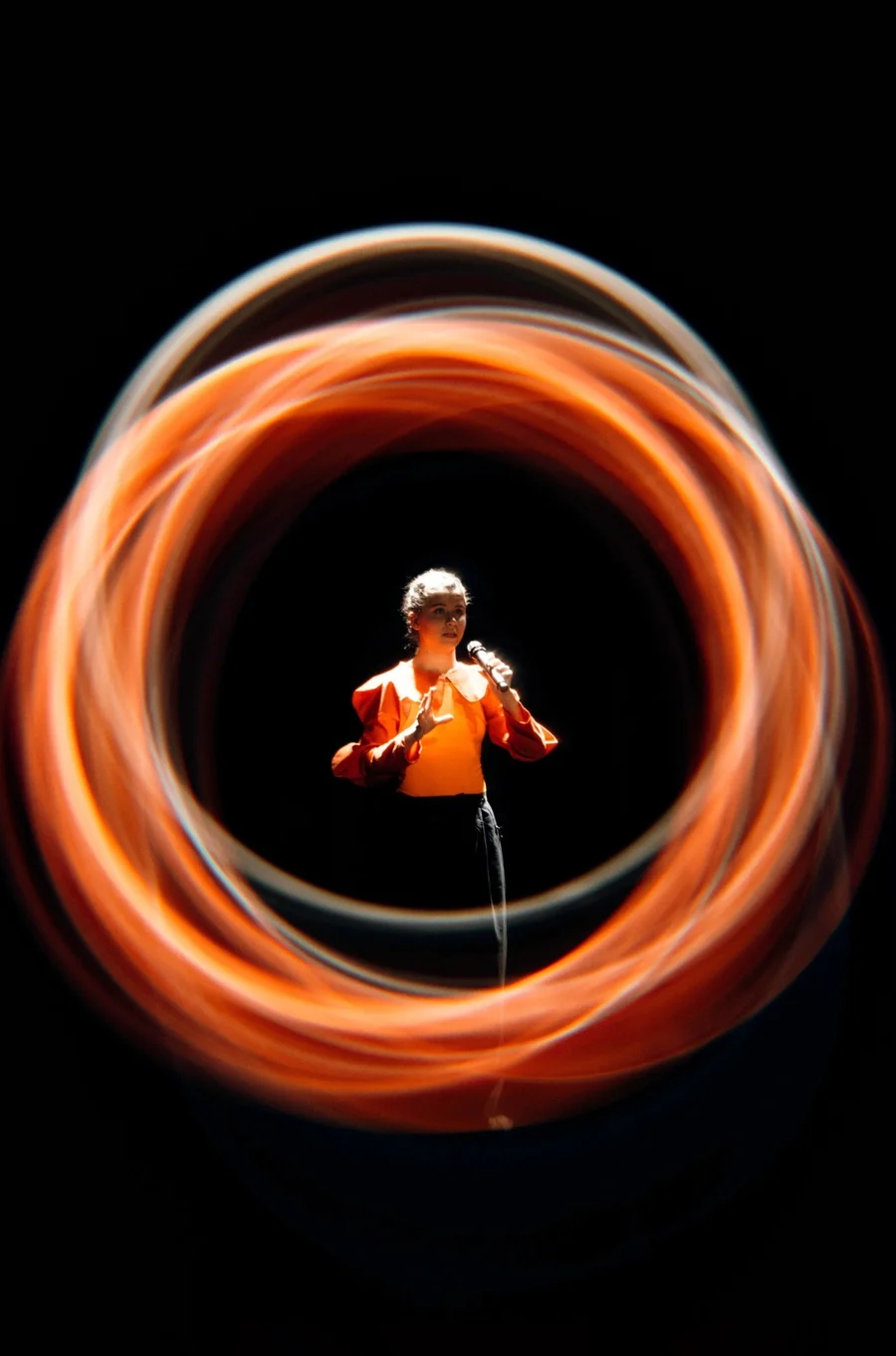 Performer surrounded by circular orange light trails