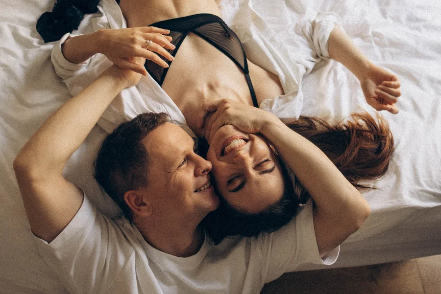 Couple laughing together while lying on a bed