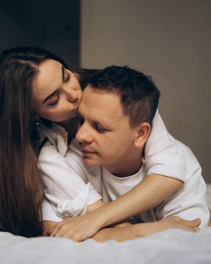 Couple embracing, with a woman kissing her partner on the head